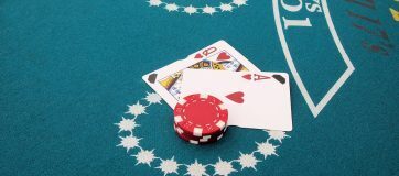 Online Blackjack. Play like a pro with strategies. Image shows Blackjack table, tow cards and betting chips.